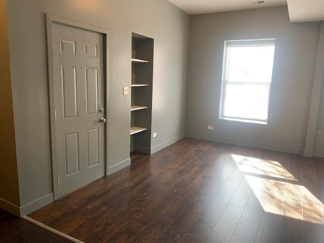 unfurnished bedroom featuring dark wood-style flooring, visible vents, and baseboards