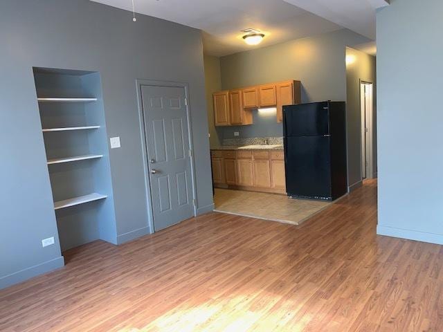 kitchen with light wood-style floors, baseboards, built in features, and freestanding refrigerator