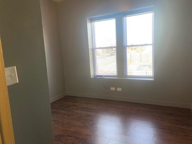 empty room featuring baseboards and dark wood-style flooring