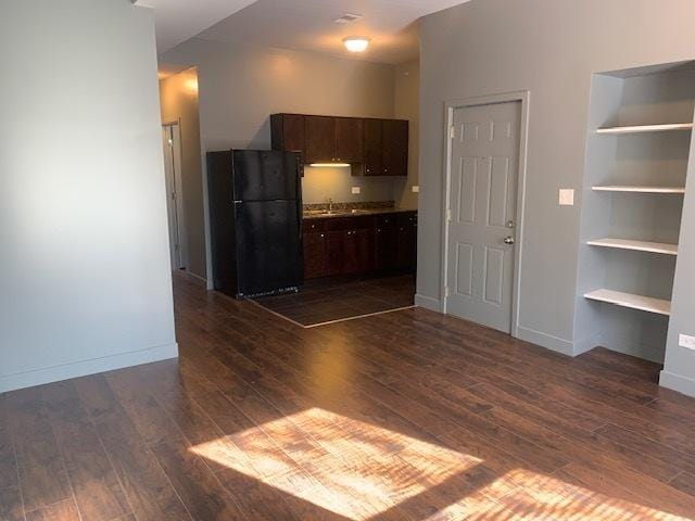 kitchen with dark wood-style floors, baseboards, dark brown cabinets, and freestanding refrigerator