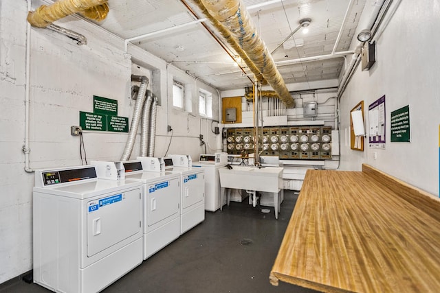 community laundry room featuring concrete block wall, washer and clothes dryer, and a sink