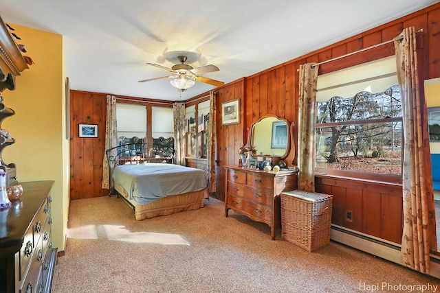 bedroom with a baseboard heating unit, carpet, ceiling fan, and wooden walls