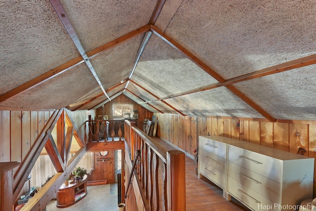 additional living space featuring vaulted ceiling, a baseboard radiator, wood finished floors, and wooden walls