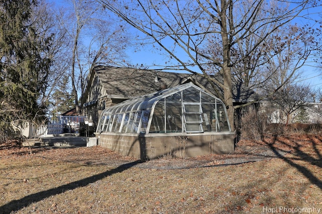 view of side of home with a shingled roof and an exterior structure