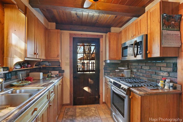 kitchen with light tile patterned flooring, a sink, wood ceiling, appliances with stainless steel finishes, and beam ceiling