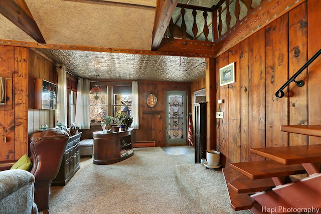 carpeted living area with a baseboard radiator and wooden walls