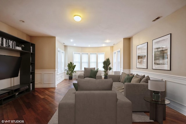 living room featuring visible vents, dark wood-style floors, wainscoting, and a decorative wall