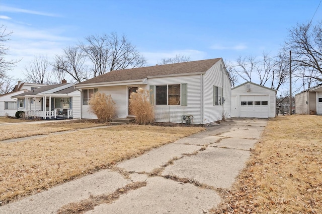 view of front of house featuring an outbuilding, a detached garage, concrete driveway, covered porch, and a front yard