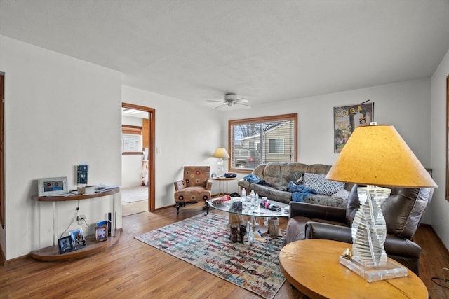 living area with a ceiling fan and wood finished floors