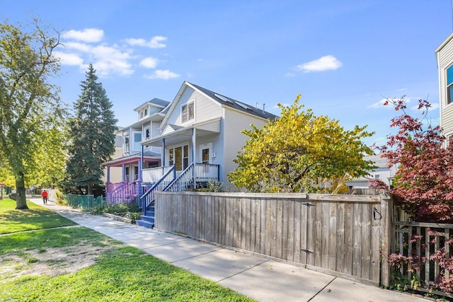 view of front of home with a porch, a fenced front yard, and a front yard