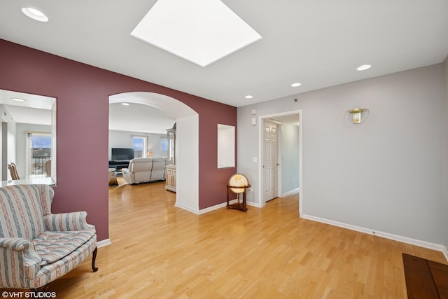 sitting room featuring arched walkways, recessed lighting, light wood-style flooring, and baseboards