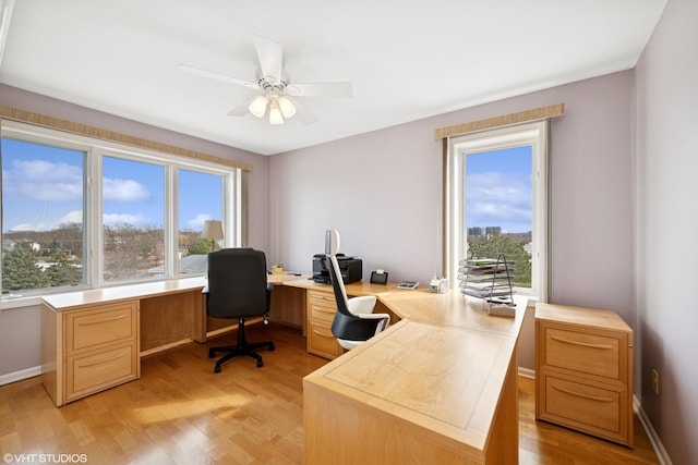 office space featuring a ceiling fan, baseboards, and light wood finished floors