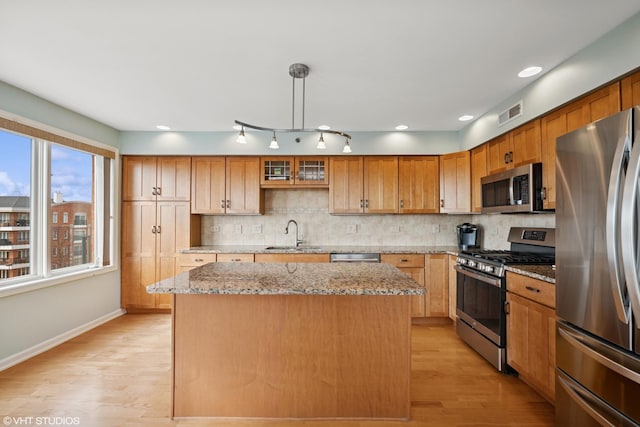 kitchen with visible vents, a sink, a kitchen island, tasteful backsplash, and stainless steel appliances