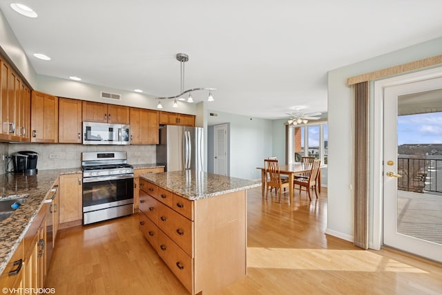 kitchen featuring visible vents, light wood-type flooring, appliances with stainless steel finishes, tasteful backsplash, and a center island