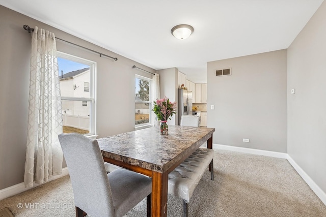 dining room featuring light colored carpet, visible vents, and baseboards