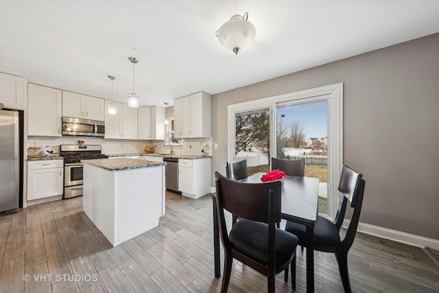 kitchen with tasteful backsplash, appliances with stainless steel finishes, wood finished floors, and a center island