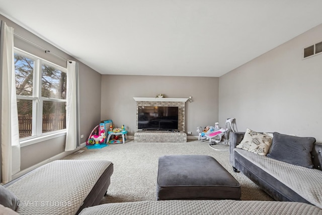 carpeted living area with baseboards, a fireplace, and visible vents