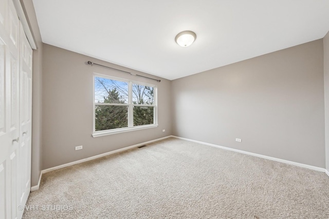 unfurnished room featuring carpet floors, visible vents, and baseboards