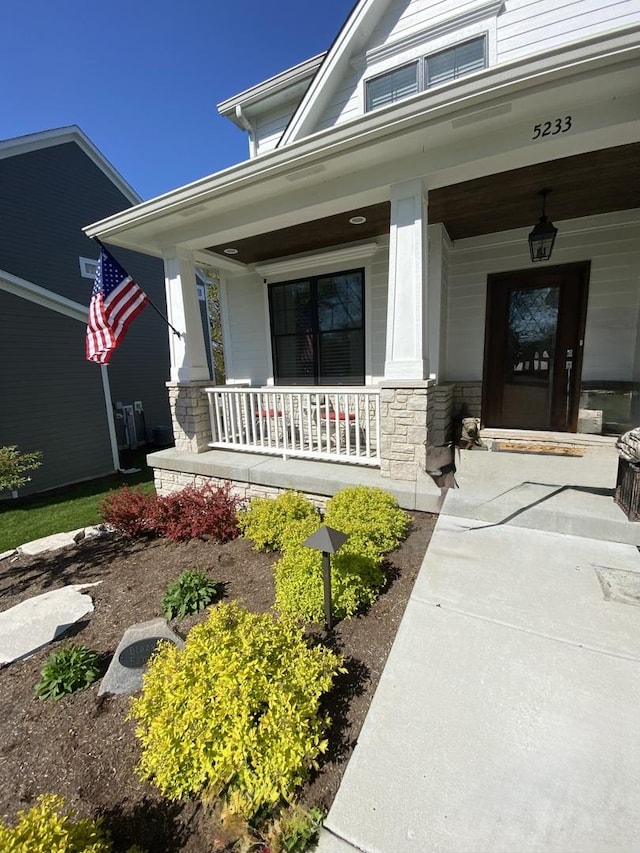 view of exterior entry featuring stone siding and a porch