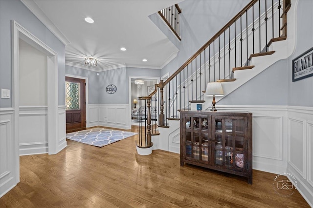 entrance foyer with wood finished floors, recessed lighting, stairway, crown molding, and a decorative wall