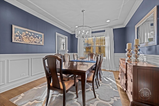 dining room with a wainscoted wall, wood finished floors, crown molding, and a chandelier