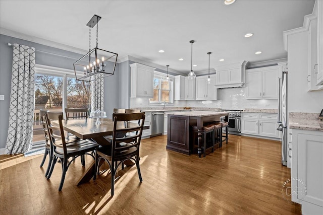 dining space featuring recessed lighting, ornamental molding, and wood finished floors