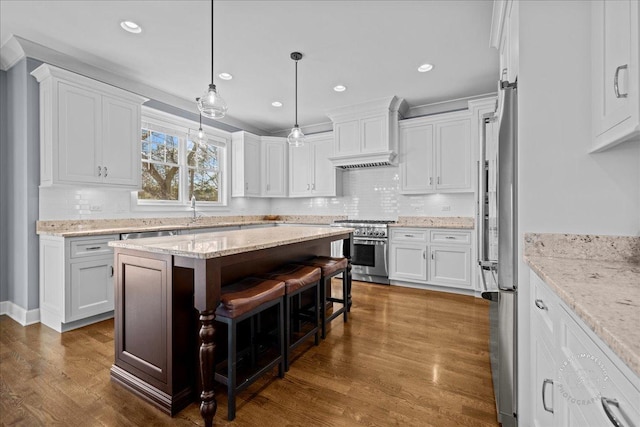 kitchen with wall chimney range hood, stainless steel stove, white cabinets, and dark wood-style floors