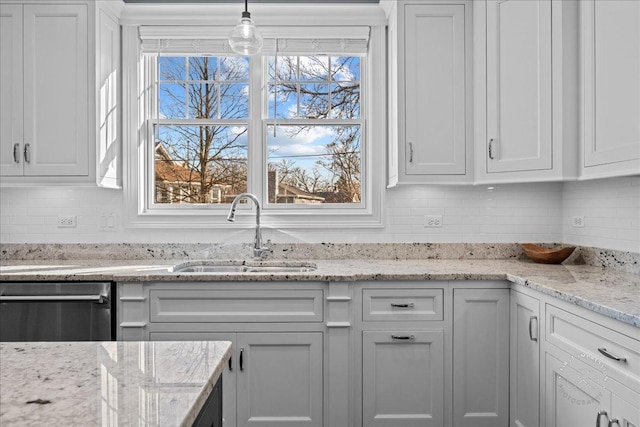 kitchen featuring decorative backsplash, white cabinets, stainless steel dishwasher, and a sink