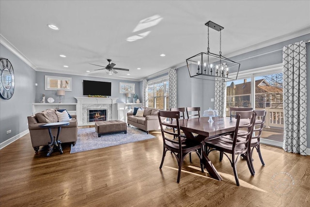 dining area with wood finished floors, a high end fireplace, recessed lighting, crown molding, and baseboards