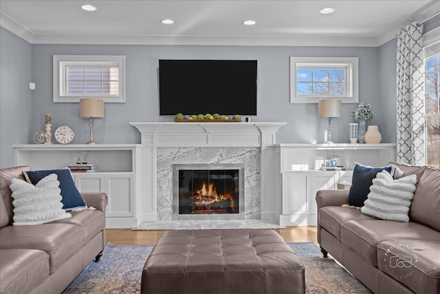 living room with ornamental molding, recessed lighting, wood finished floors, and a premium fireplace