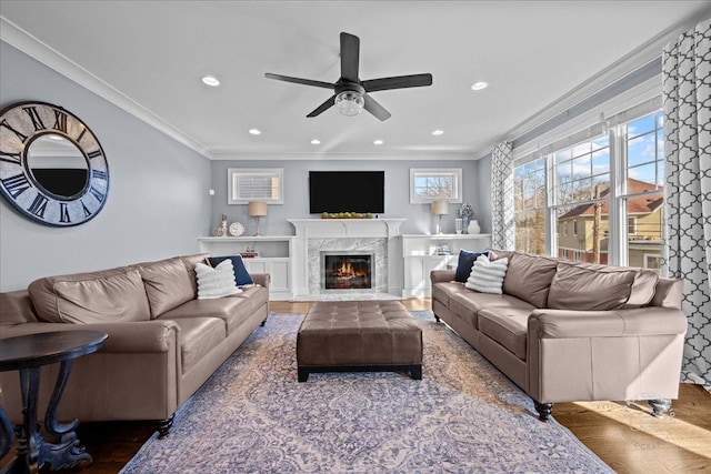 living room with wood finished floors, recessed lighting, a fireplace, crown molding, and ceiling fan