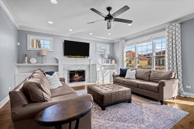 living area featuring wood finished floors, a high end fireplace, recessed lighting, crown molding, and baseboards