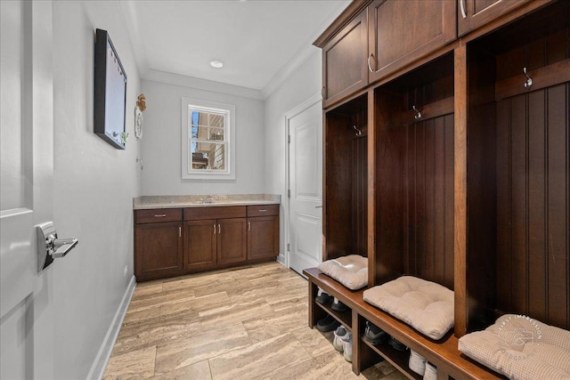 mudroom with a sink, baseboards, and ornamental molding