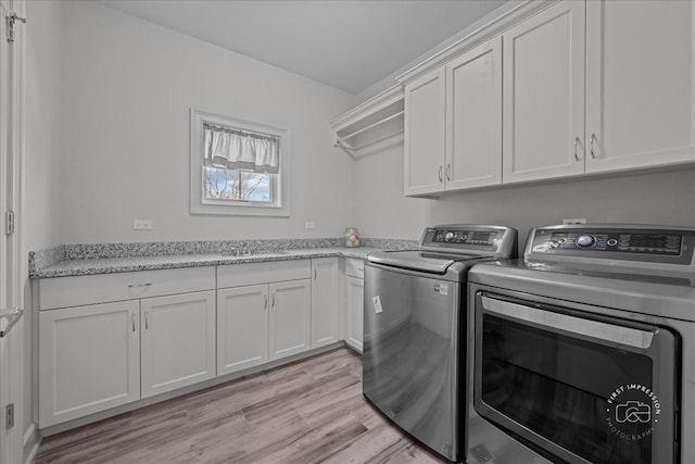 laundry room featuring a sink, cabinet space, independent washer and dryer, and light wood-type flooring