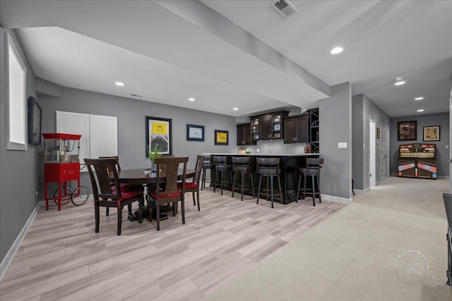 dining space with recessed lighting, visible vents, bar, and baseboards