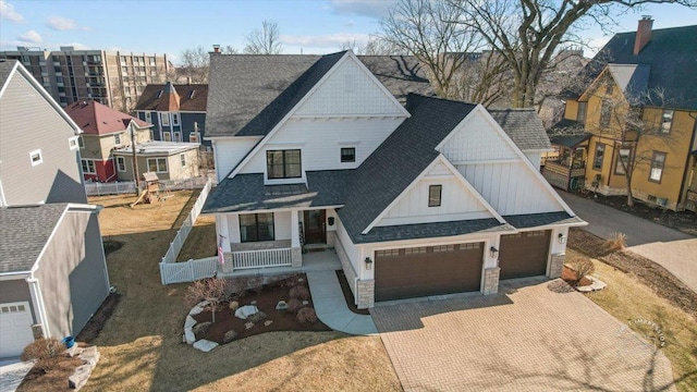 view of front of house featuring decorative driveway, stone siding, a porch, an attached garage, and a shingled roof