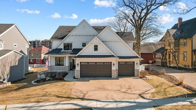 view of front facade with board and batten siding, a porch, decorative driveway, a garage, and stone siding