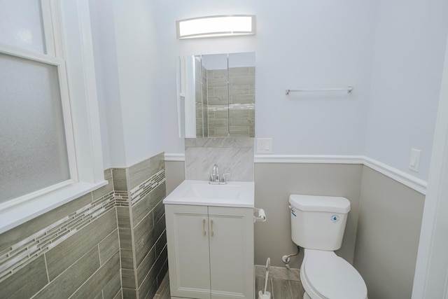 bathroom featuring tile walls, vanity, and toilet