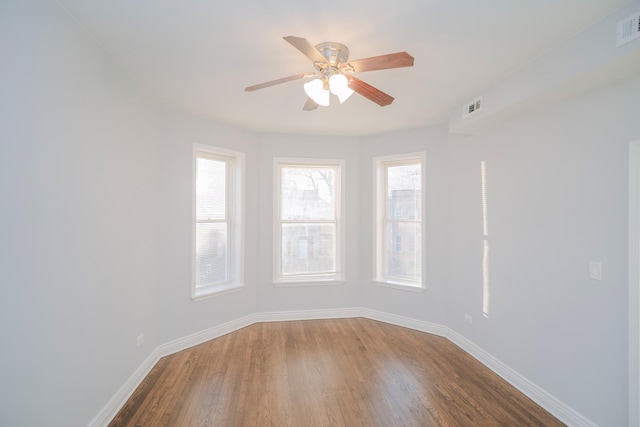 empty room with a ceiling fan, visible vents, baseboards, and wood finished floors