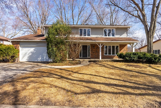 traditional-style home featuring driveway, an attached garage, a front yard, brick siding, and a chimney