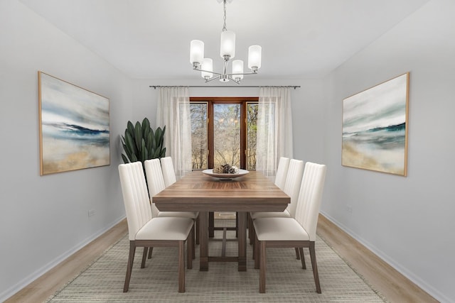 dining room featuring light wood-type flooring, baseboards, and a chandelier