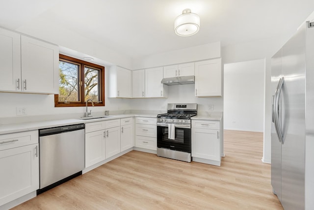 kitchen with a sink, light countertops, under cabinet range hood, appliances with stainless steel finishes, and white cabinetry