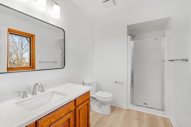 bathroom featuring visible vents, toilet, a stall shower, wood finished floors, and vanity