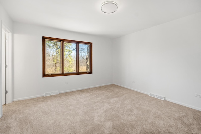 carpeted spare room with visible vents and baseboards