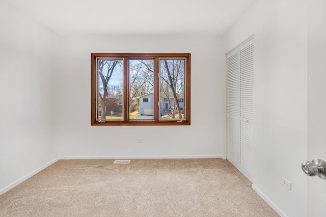 carpeted spare room featuring baseboards and visible vents