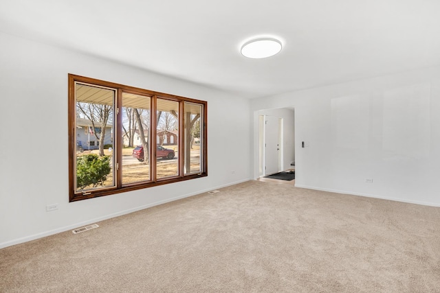 spare room with carpet, visible vents, and baseboards