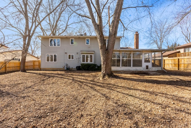 rear view of house with fence, a chimney, and a sunroom