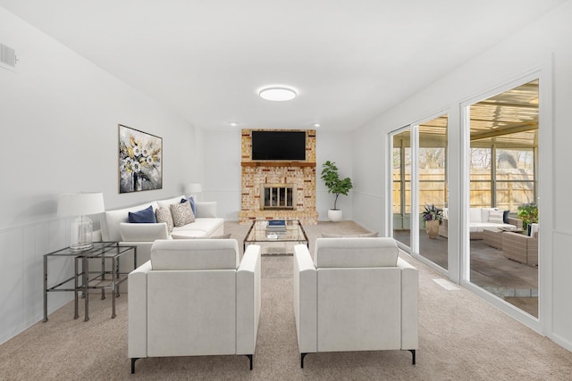 carpeted living area featuring visible vents, a wainscoted wall, and a fireplace