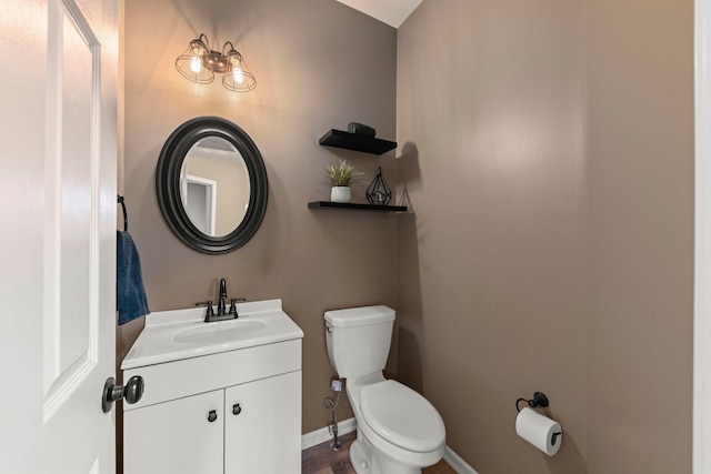 half bathroom featuring toilet, baseboards, and vanity