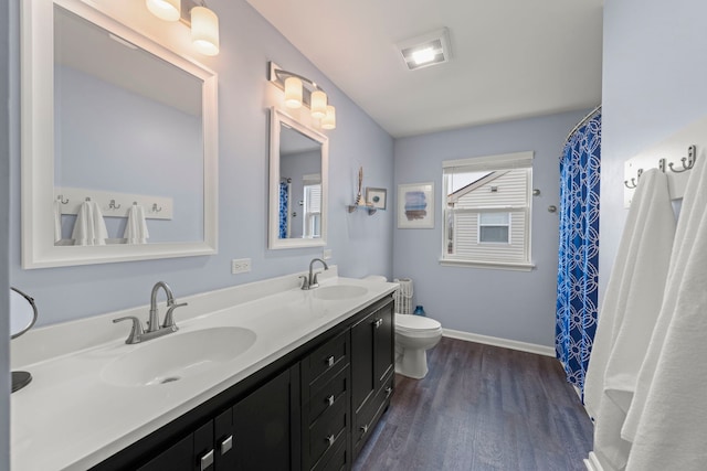 full bathroom featuring double vanity, a sink, toilet, and wood finished floors